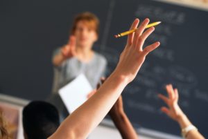 Teacher pointing to raised hands in classroom